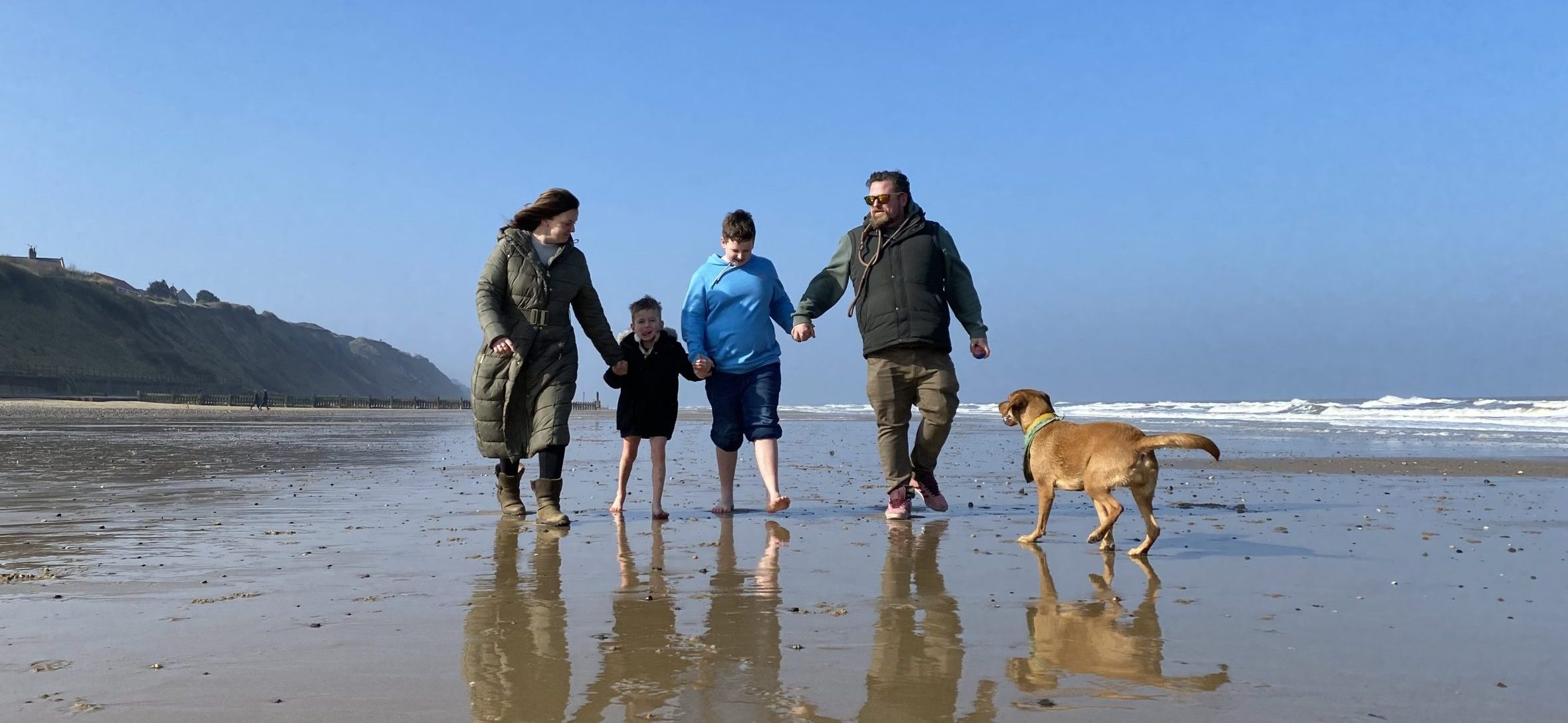 Albie and his family walk on a beach.