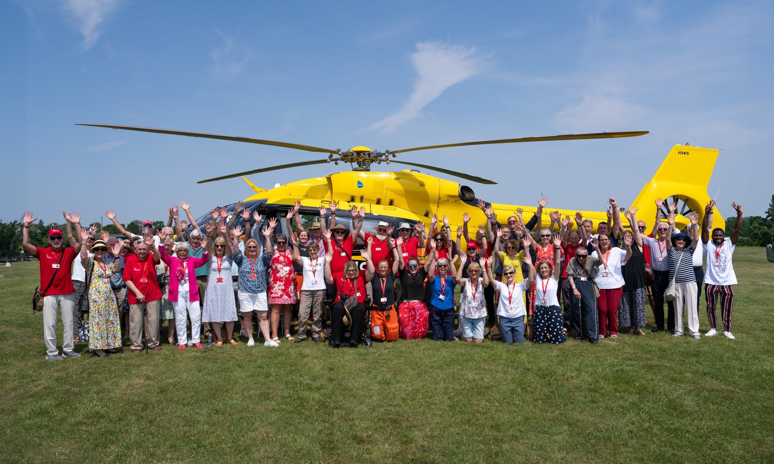 EAAA volunteers standing in front of yellow helicopter