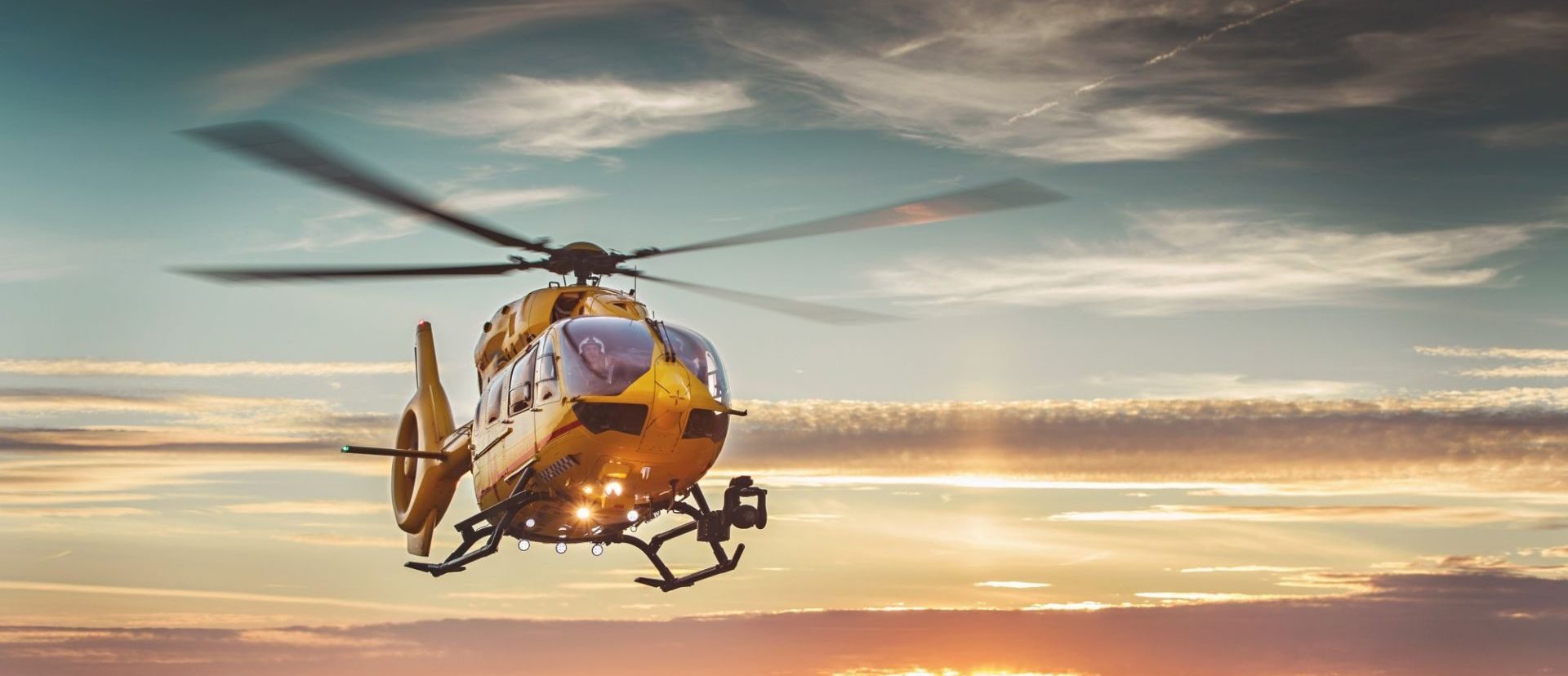 East Anglian Air Ambulance helicopter landing at sunset