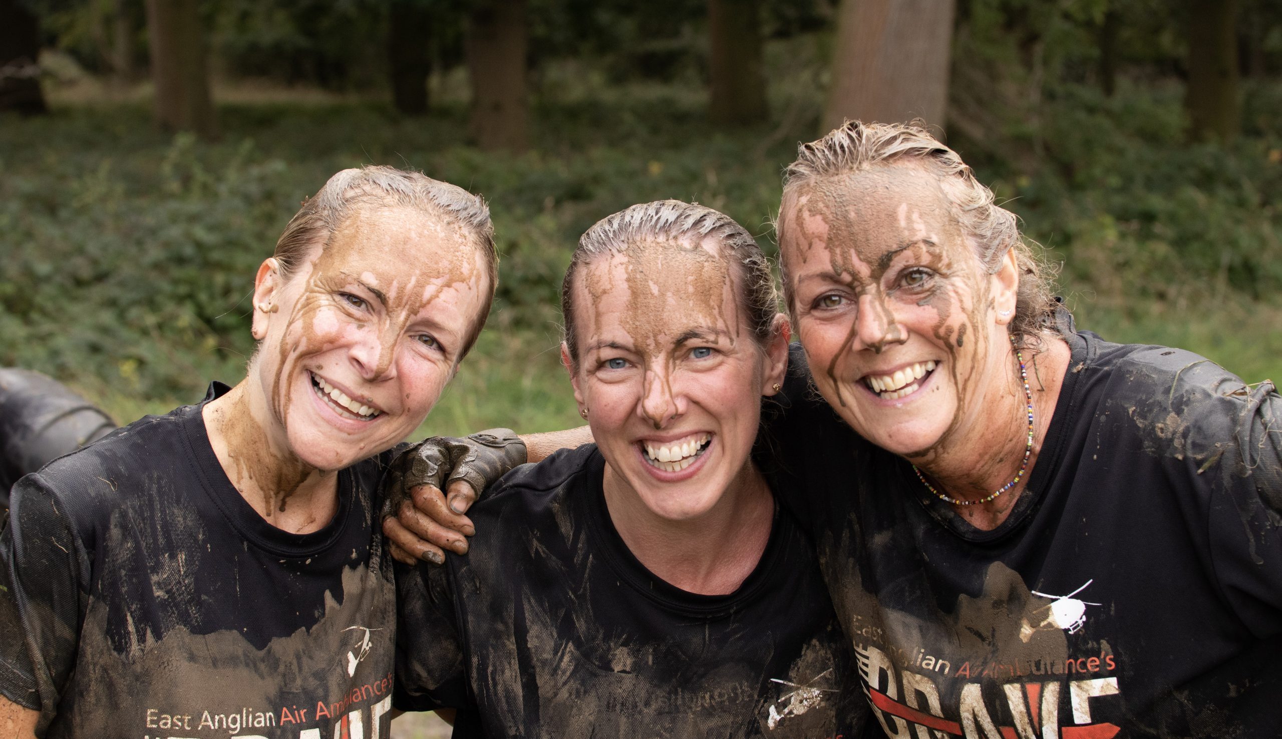 Three female Only The Brave participants covered in mud