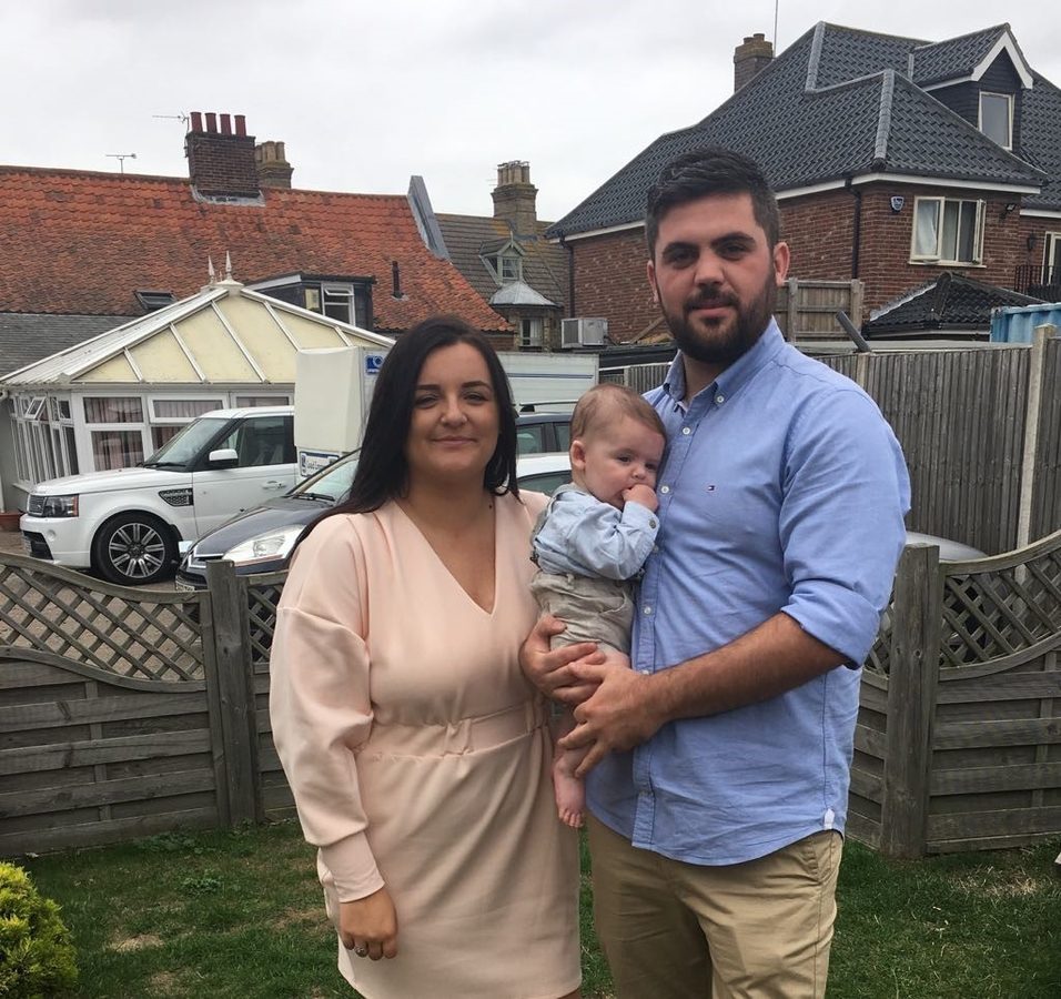 Tom Port with his partner and baby in his garden at home. 