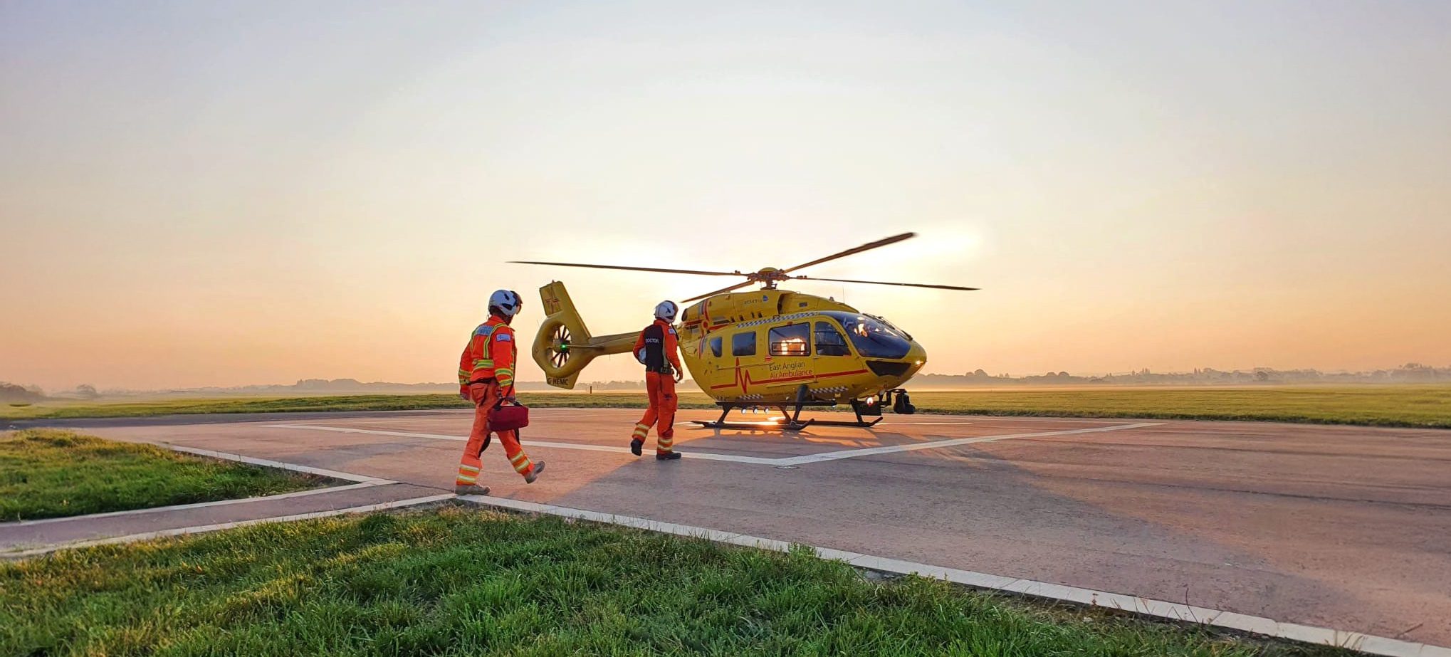 Crew walk out to helicopter at sunset