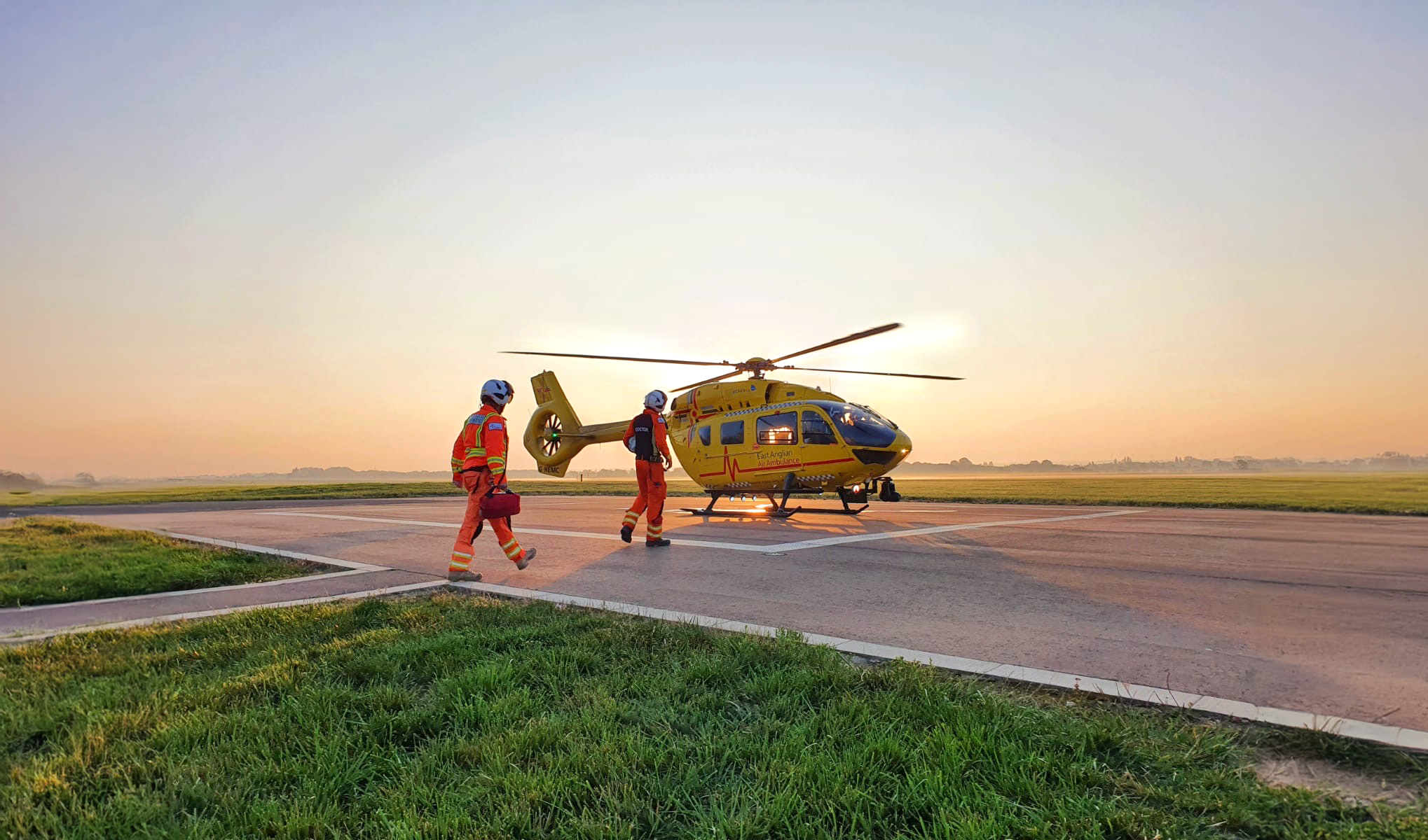 Crew walk out to helicopter at sunset