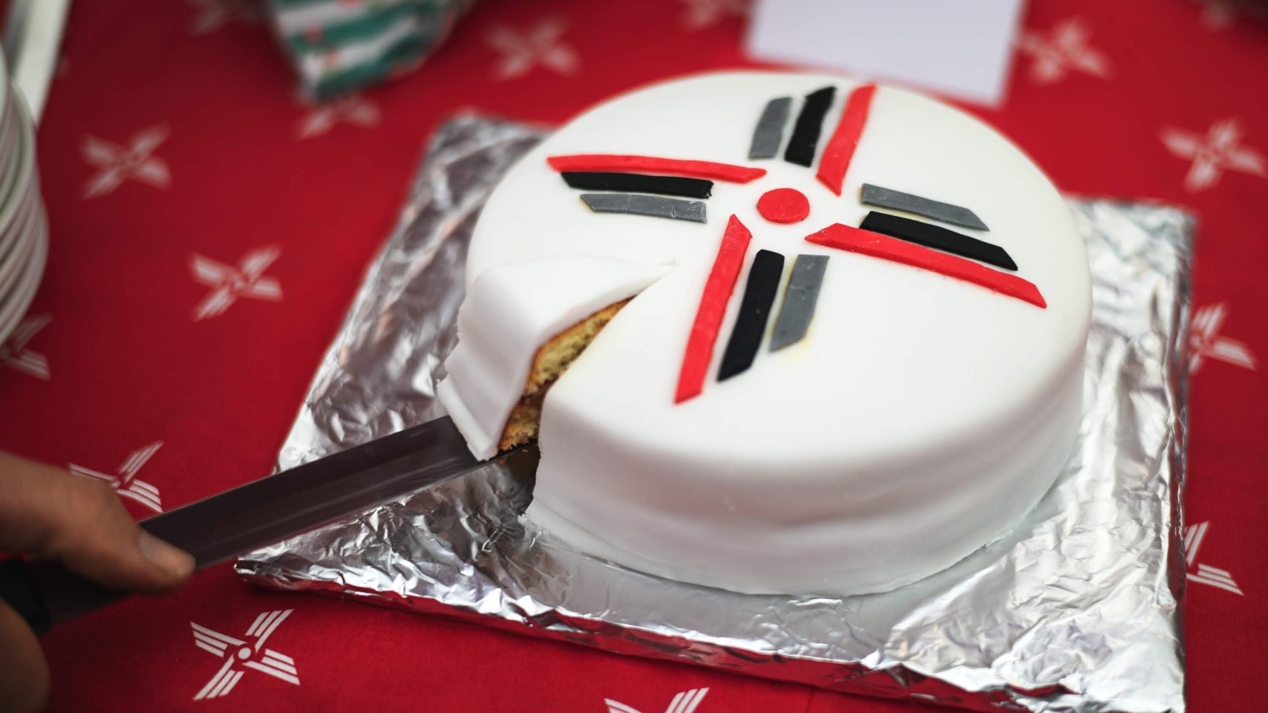 Cake being cut with EAAA logo on top