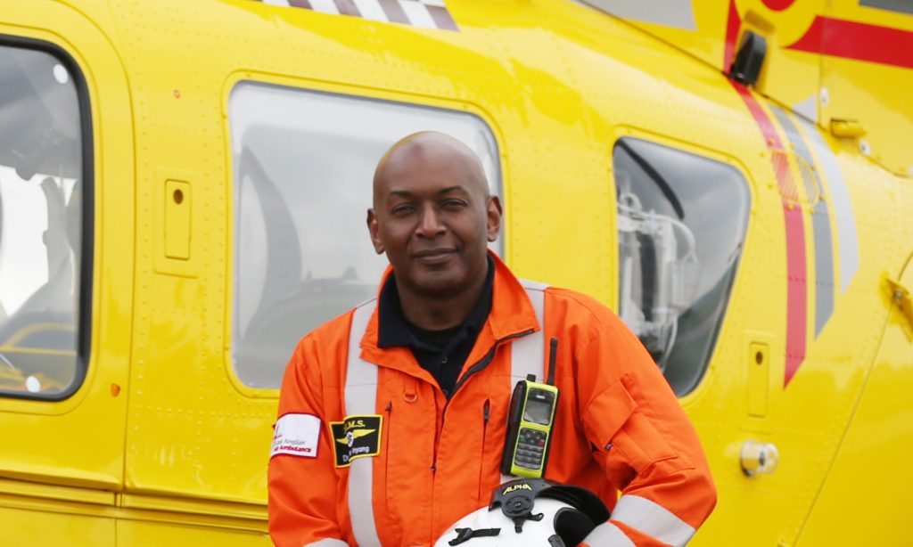 EAAA Medical Director, Dr Victor Inyang standing in front of yellow helicopter