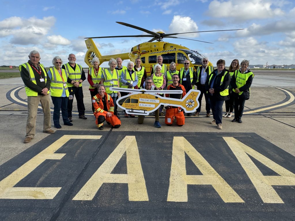 Kevin Marshall and volunteers with cheque and helicopter