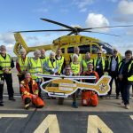 Kevin Marshall and volunteers with cheque and helicopter